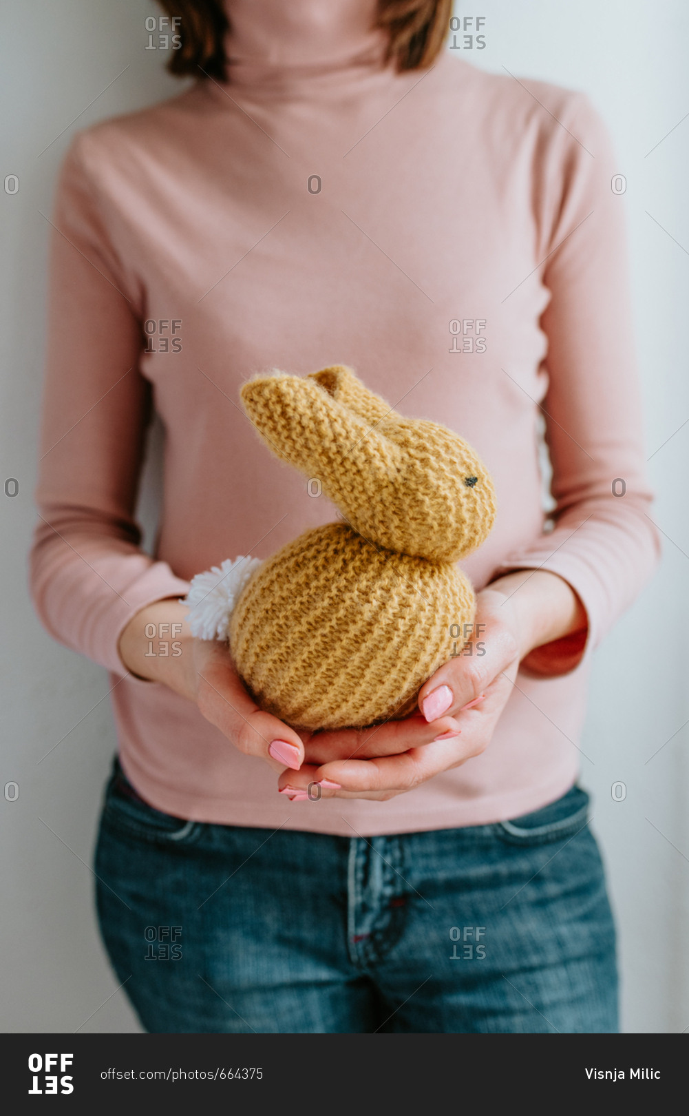 Person wearing pink shirt holding cute knitted Easter bunny
