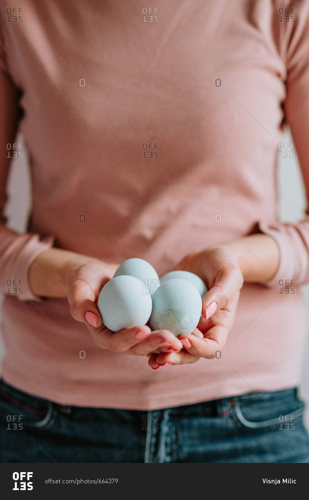Woman wearing pastel colors holding pastel Easter eggs in her hands