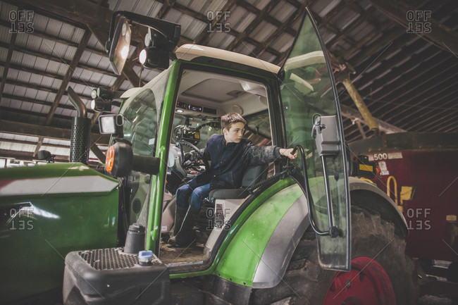 Teenage boy operating tractor on farm, Chilliwack, British Columbia, Canada