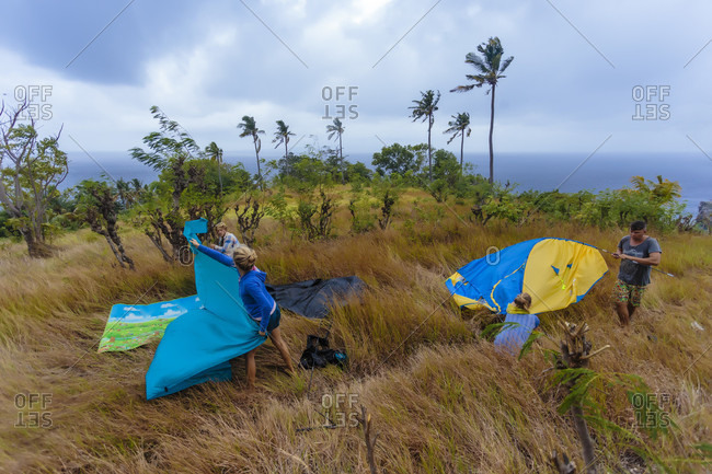 People setting up tent in meadow, Nusa Penida, Bali, Indonesia