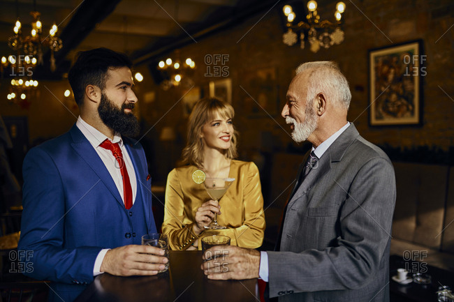 Two elegant men and woman socializing in a bar