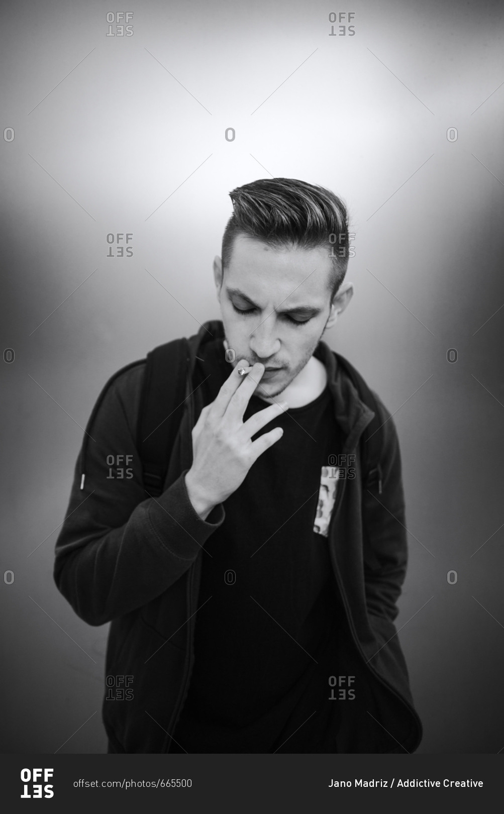 Black and white portrait of casual young man smoking cigarette and ...