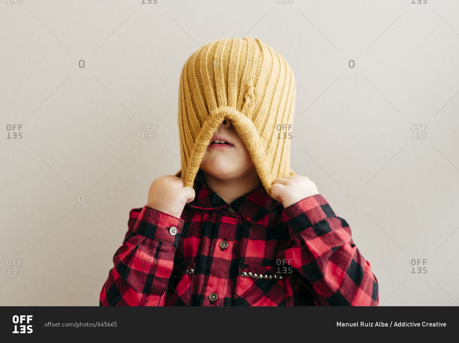 Cute boy covering face with wool cap