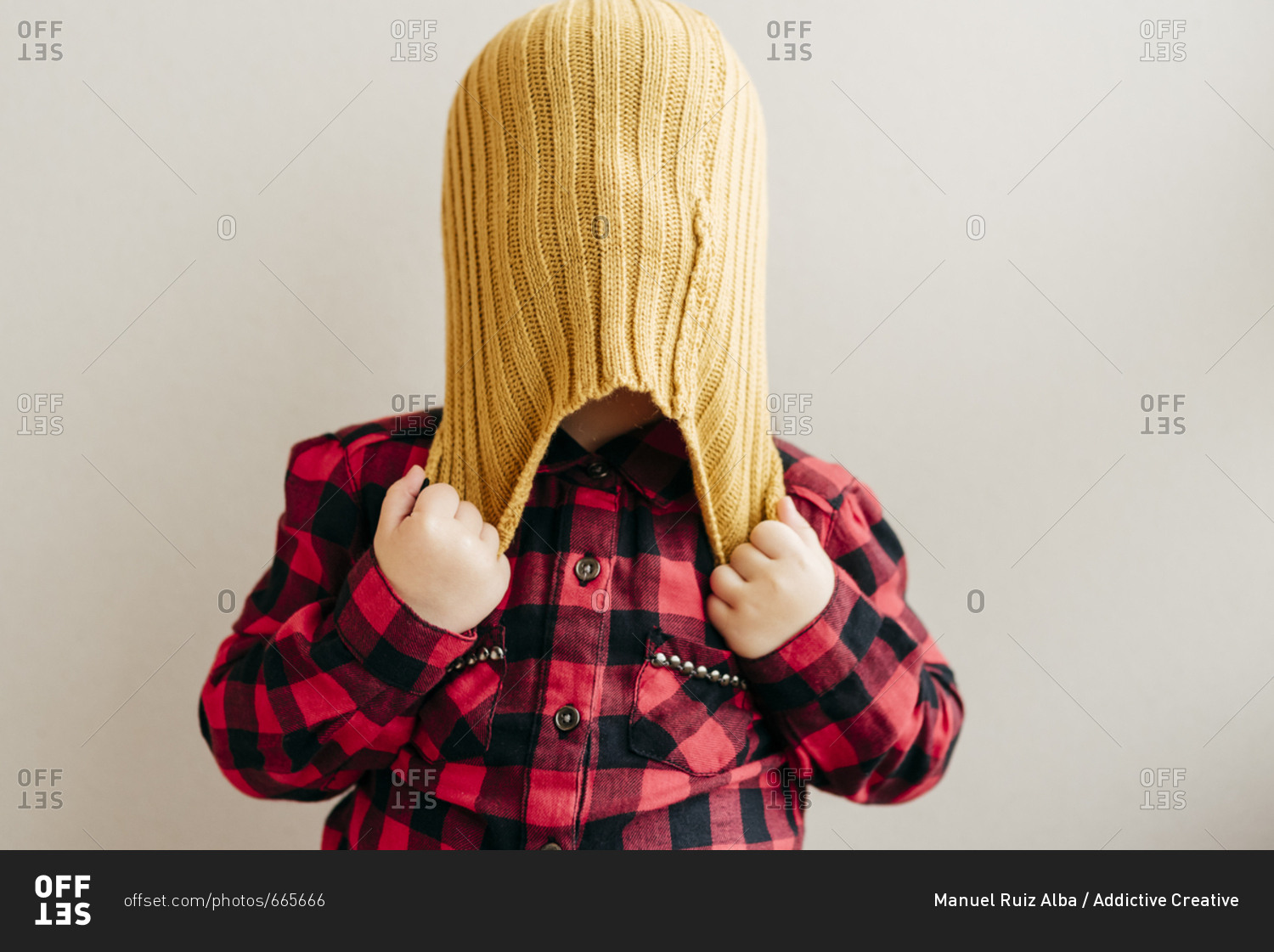 Cute boy covering face with wool cap