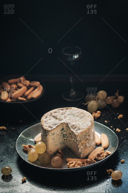 Blue cheese with grapes, walnuts in dark background