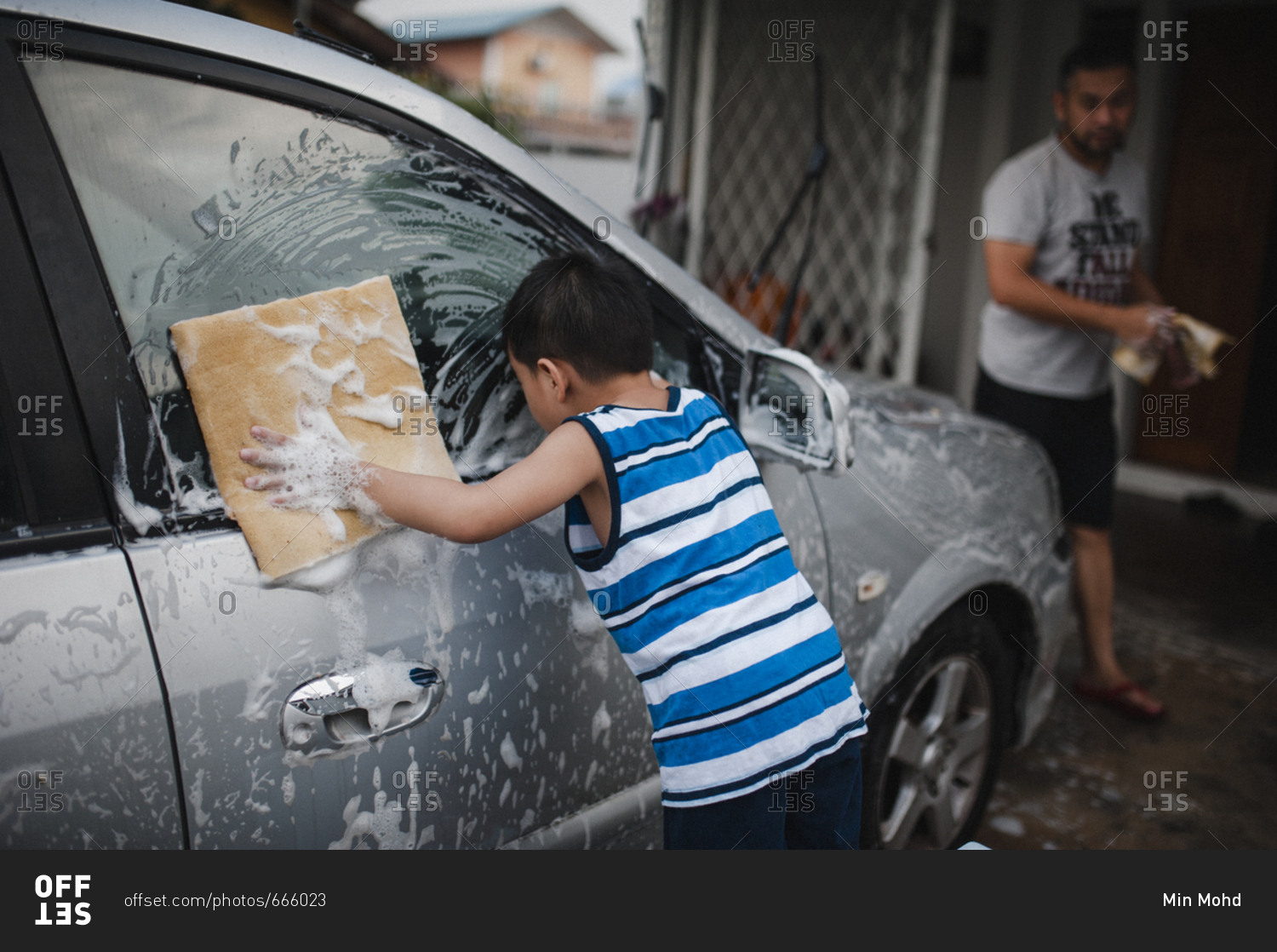 Little boy and his dad washing a car