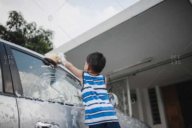 Little boy washing car with soapy sponge