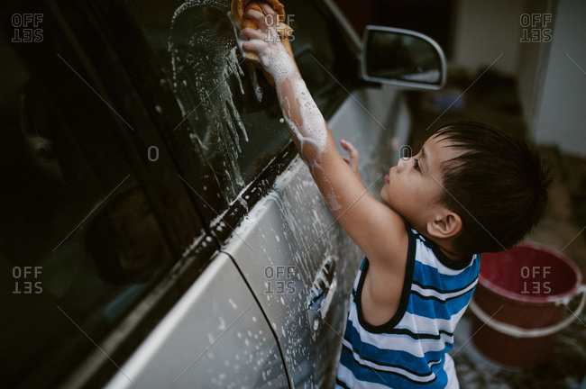 Young boy washing car with soapy rag