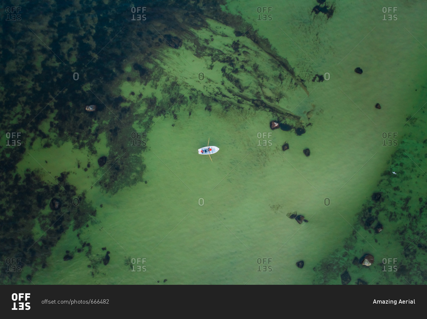 Aerial view of two people fishing in a small wooden boat in the middle of the green baltic sea in Estonia