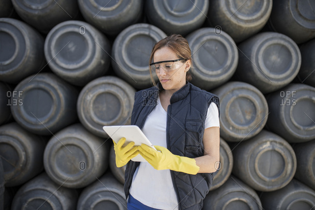 Worker woman with barrel background and work clothes. Protective glasses and gloves.