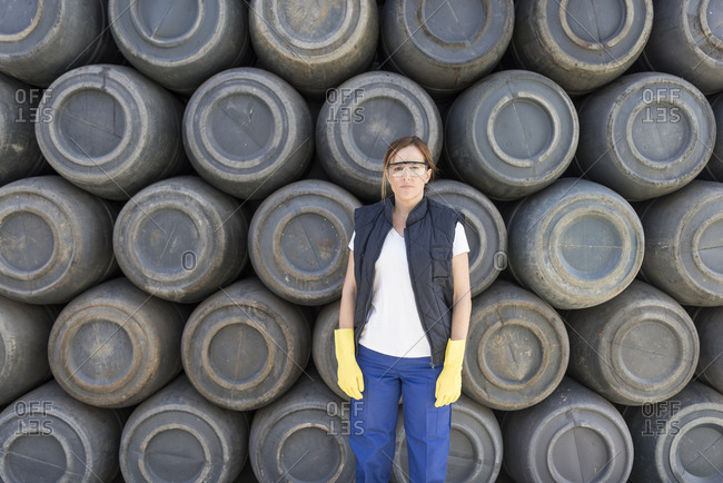 Worker woman with barrel background and work clothes. Protective glasses and gloves.