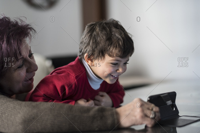 Grandmother and grandson looking smartphone at home in home living room