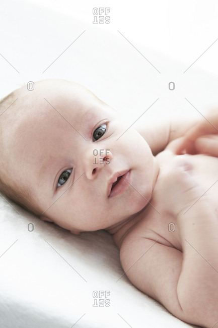 One month old baby boy being on wedge looking at camera