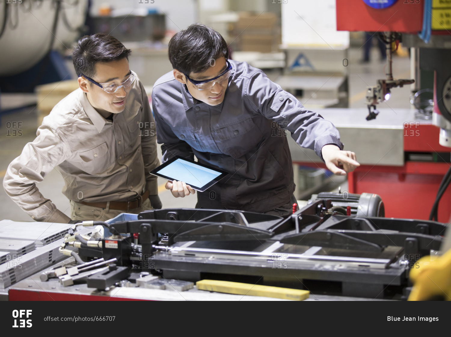 Confident Chinese engineers talking in the factory stock photo - OFFSET