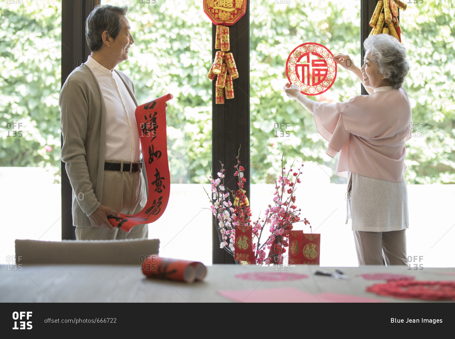 Cheerful senior couple decorating their house for Chinese New Year