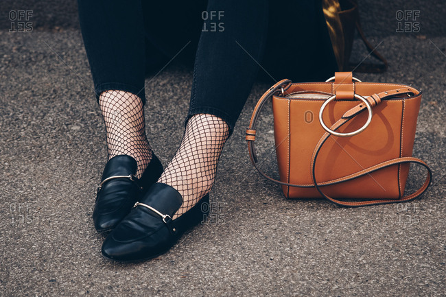 Close-up of woman\'s leather shoes and purse sitting on ground