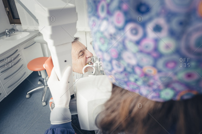 Dentist using dental equipment while examining patient's teeth