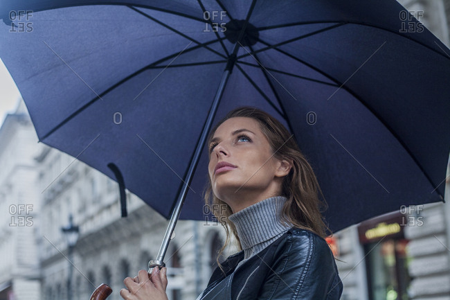 Young woman, contemplating the weather under an umbrella
