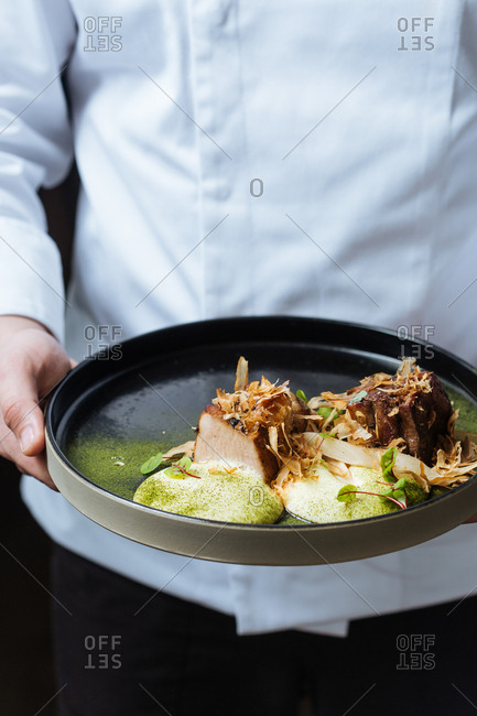Chef holding a pork belly dish