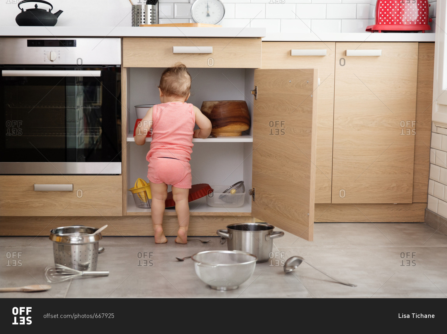 Rear view of baby making mess of kitchen cabinets