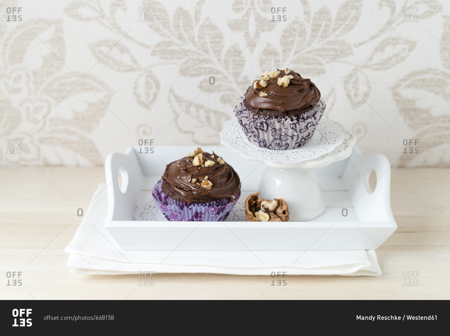Two cup cakes with chocolate cream and cracked walnuts in paper cup