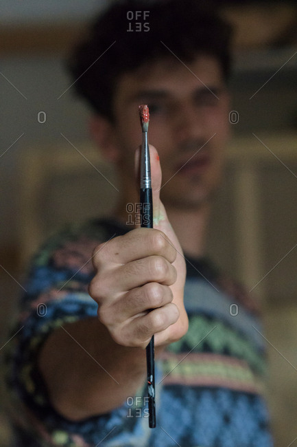 Male artist holding paintbrush in artists studio, close up