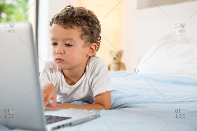 boy-using-laptop-on-bed-stock-photo-offset