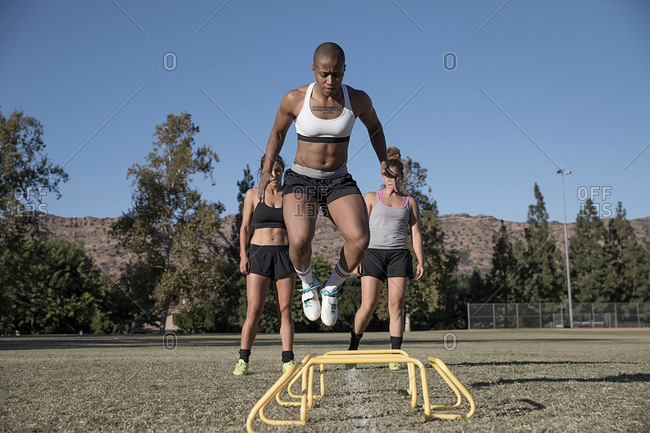 Woman jumping over agility hurdles