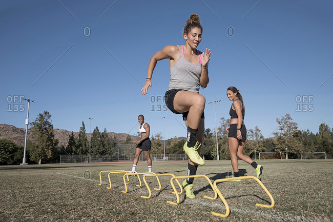 Woman jumping over agility hurdles