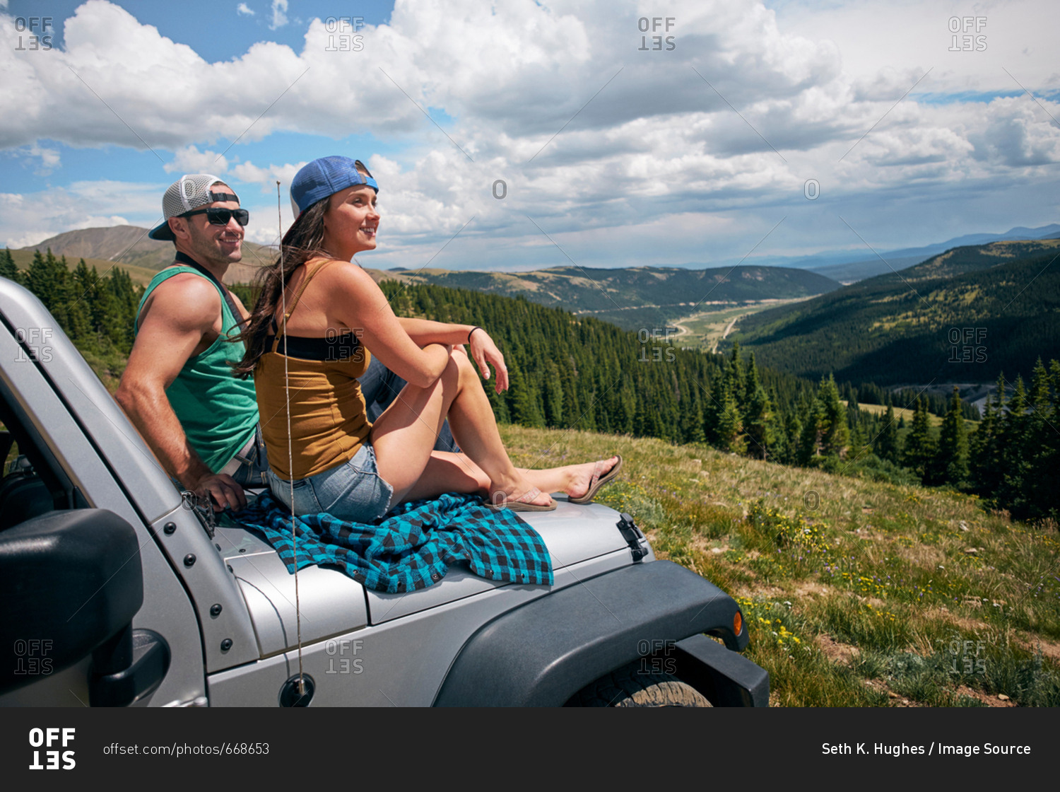 Road trip couple looking from car hood in Rocky Mountains, Breckenridge, Colorado, USA