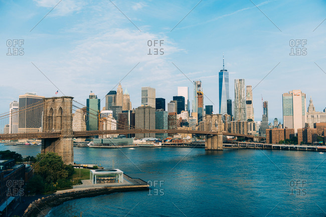 New York City - September 11, 2017: Sunny view across water of Manhattan buildings behind Brooklyn bridge