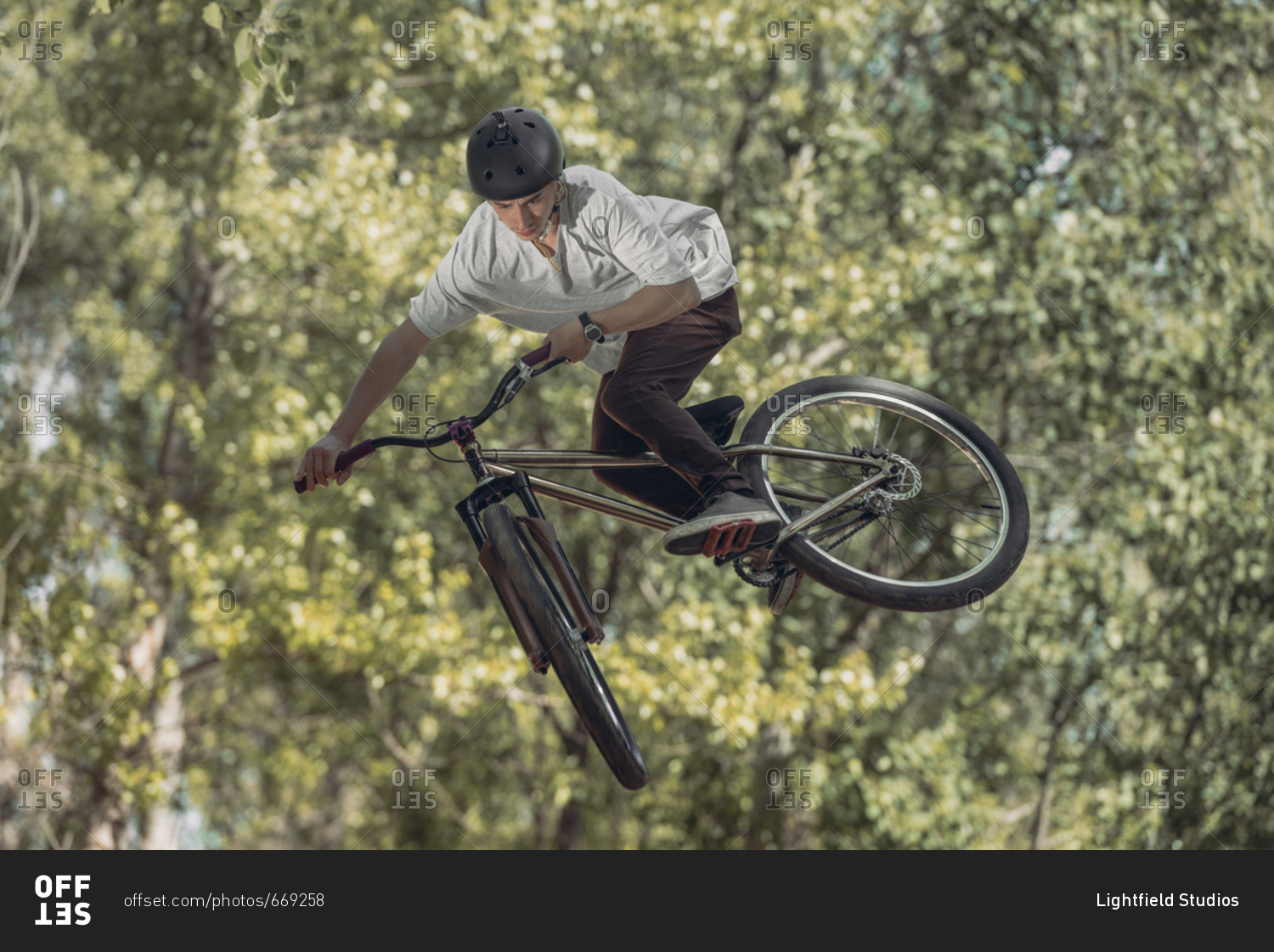 Sportsman jumping with bike with trees on blurred background