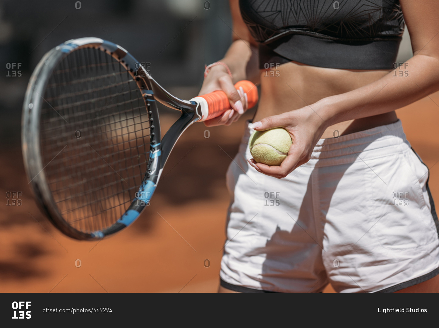 Cropped shot of athletic young woman with tennis racket and ball