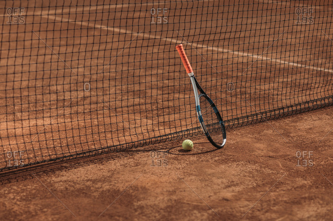 Tennis ball and racket leaning on net