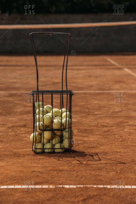 Basket of tennis balls standing on court