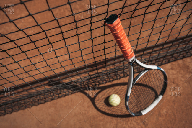 Close-up shot of tennis ball and racket leaning on net