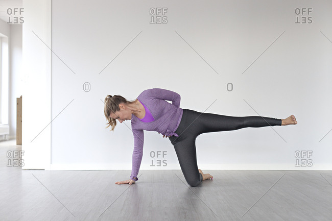 Young woman attempting balancing pose during yoga session in studio