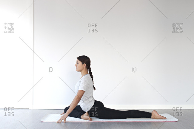 Young woman in half pigeon pose during yoga session in studio