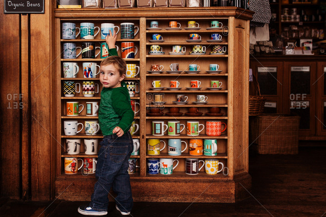 Toddler boy looking at coffee cups on store shelf
