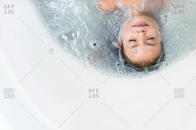 Upside down view of small child soaking in bubble bath