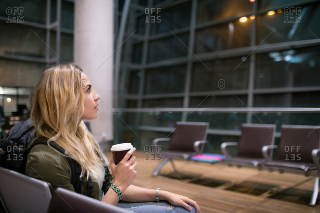 Woman having coffee while waiting in waiting area at airport terminal