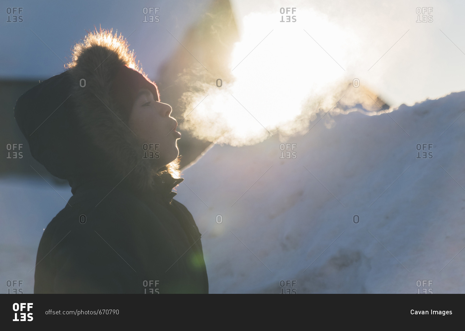 Side view of boy wearing fur coat while exhaling breath vapor during winter