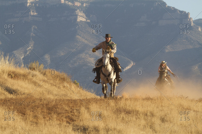 USA, Wyoming, Shell, The Hideout Ranch, Cowboy and Cowgirl Riding in Dust