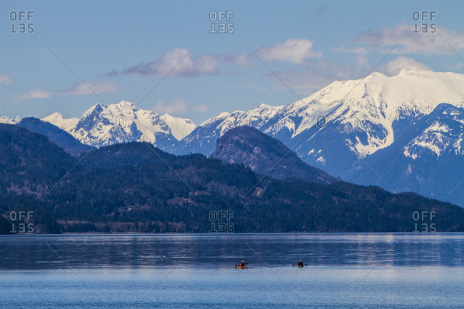 Harrison Hot Springs, British Columbia, Canada, Two people in kayaks enjoy the lake scenery of Northwest islands and snowcapped mountains