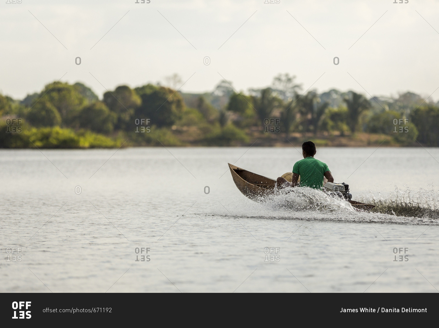 Man in a wooden motorized canoe speeds across the Amazon River near Manaus, Brazil