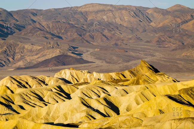 Warm light shines on the eroded hills of Golden Canyon in Death Valley National Park