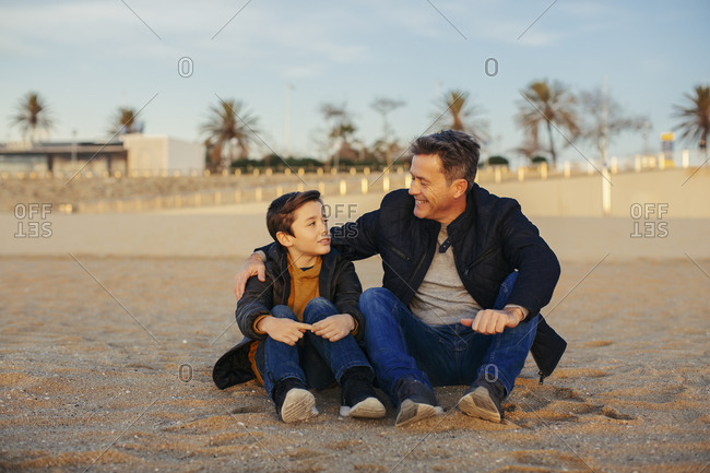 Smiling father embracing son on the beach