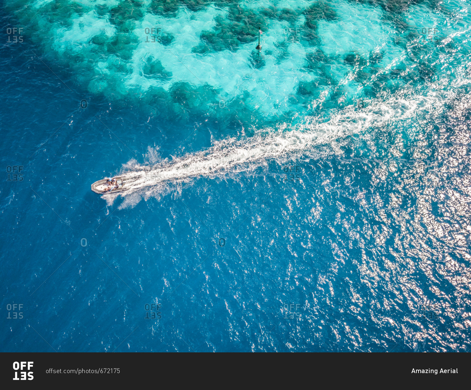 Aerial view of people in a boat in the turquoise sea of Bora-Bora, French Polynesia.