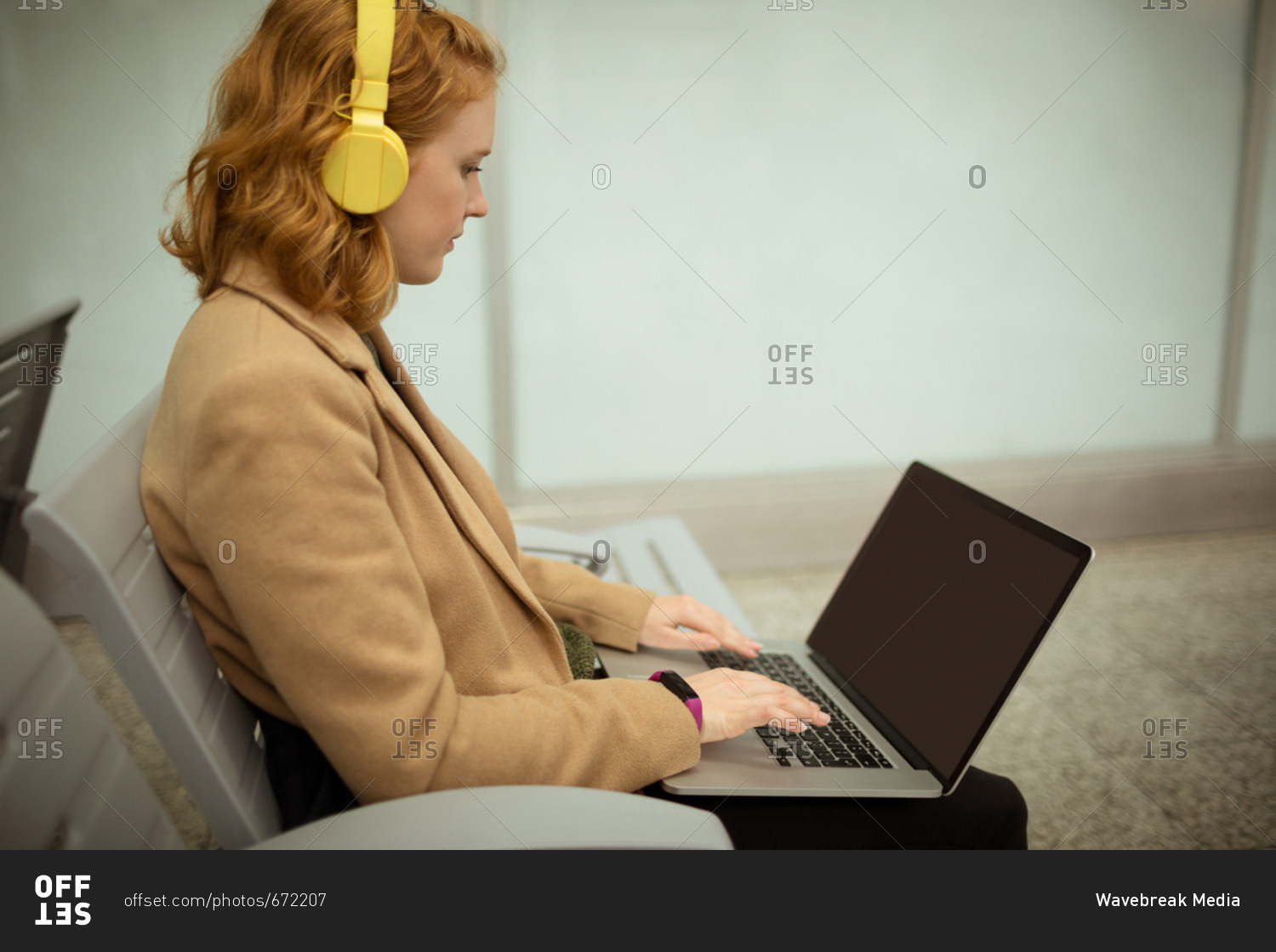 Young woman listing to music while working on laptop
