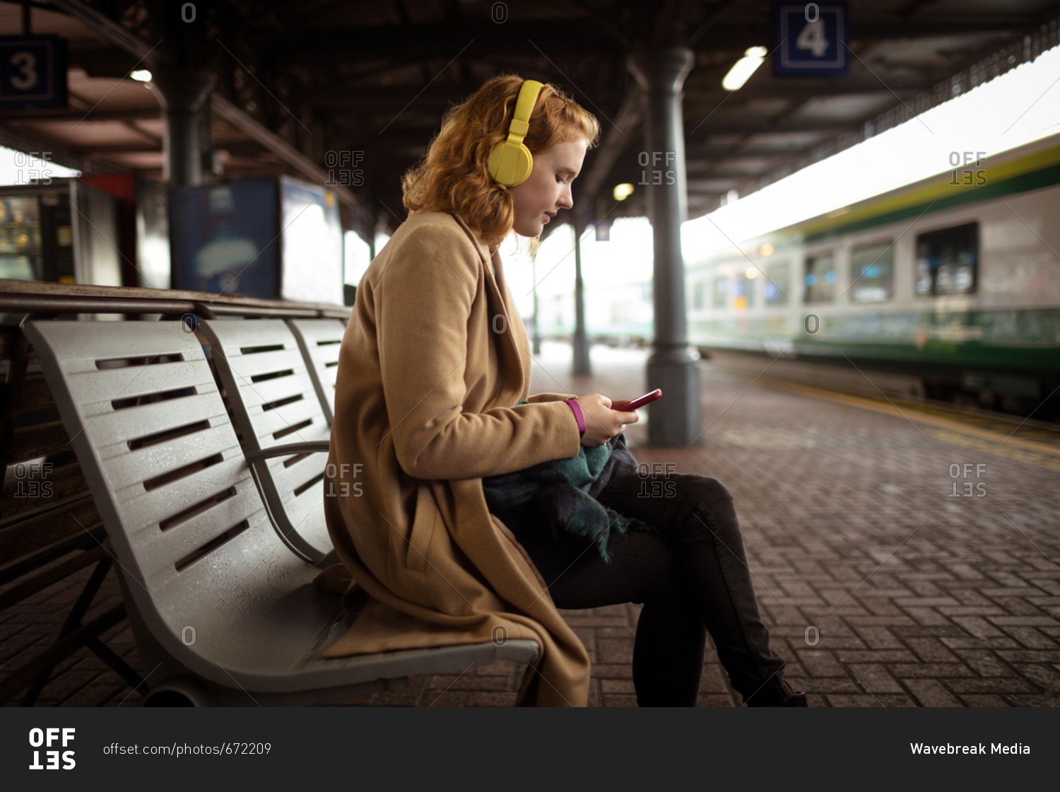Beautiful young woman listing music while using her mobile phone